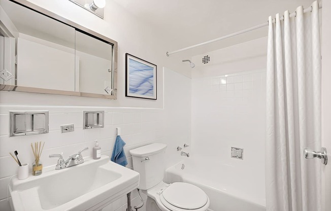 A white bathroom with a toilet, sink, and shower.
