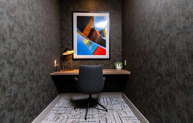 A grey chair is in front of a framed picture.