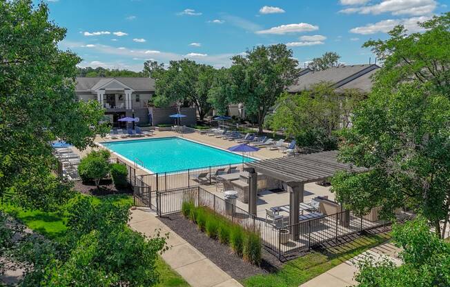 an aerial view of a swimming pool and patio with tables and chairs and a resort