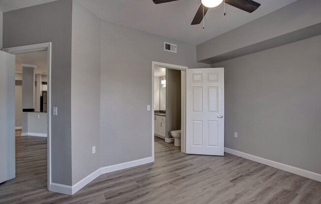 a room with a ceiling fan and a door to a bathroom