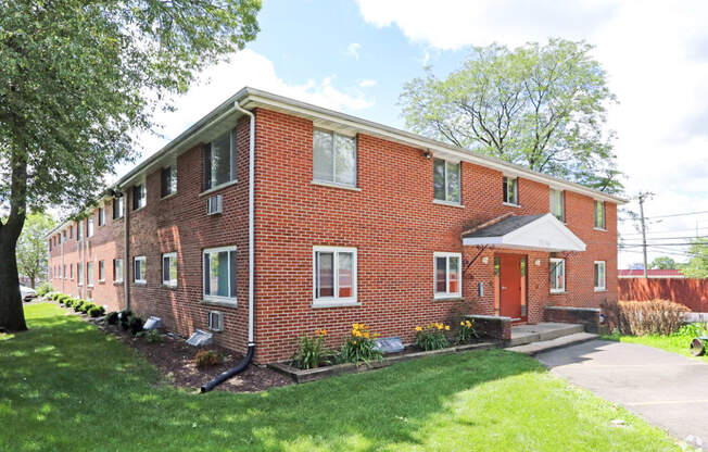 a red brick apartment building with a white car parked in front