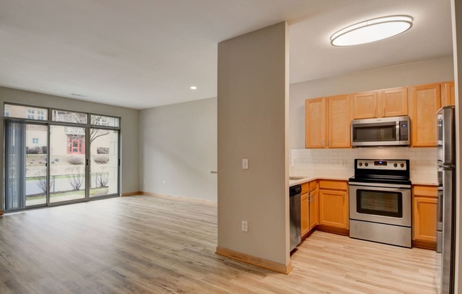 an empty kitchen and living room with wood flooring and a door to a balcony