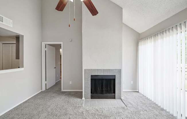 A living room with a fireplace and a ceiling fan.