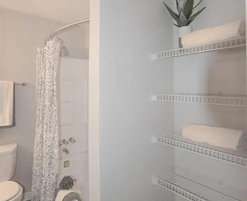 a white bathroom with a shower and a toilet at The Sapphire, Decatur, 30035