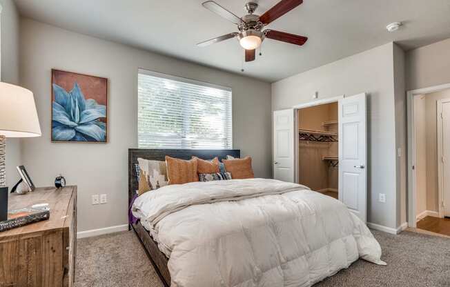 Bedroom with carpet and a ceiling fan facing the exterior window with a bed and dresser