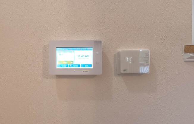 A wall-mounted thermostat and a digital clock are mounted on a wall.