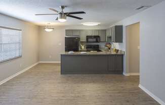 an empty kitchen and living room with a ceiling fan