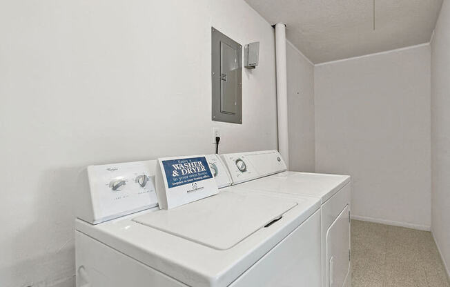 a white laundry room with two washes and a dryer