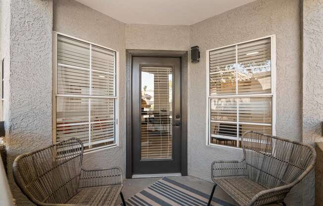 a porch with two chairs and a door