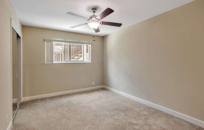 A room with a ceiling fan and carpeted floor.