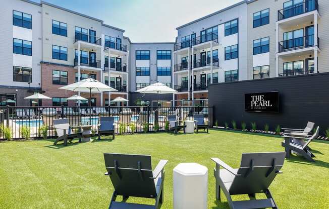 A pool area with chairs and umbrellas in front of a building with a sign that says "The Pearl".
