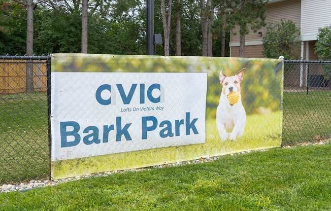 a sign that says bark park with a dog holding a tennis ball in its mouth