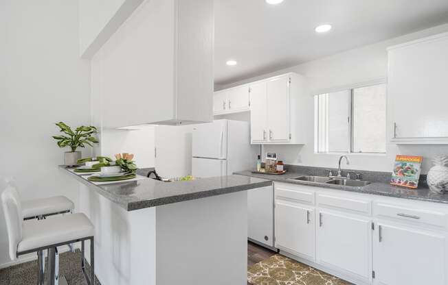 a white kitchen with white cabinets and a gray counter top