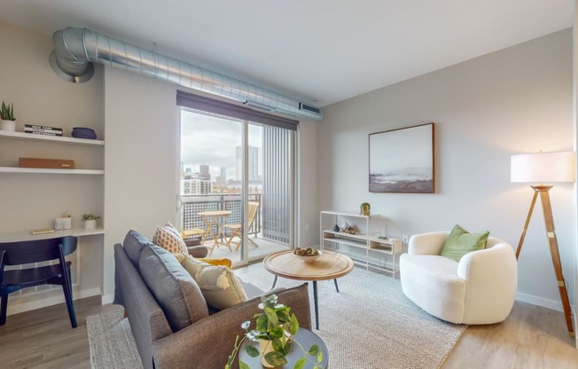 a living area with a couch chair coffee table and sliding glass door to a balcony