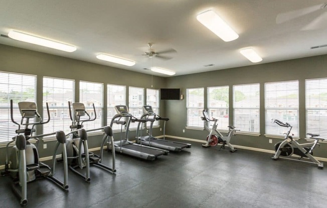 a gym with cardio equipment and windows