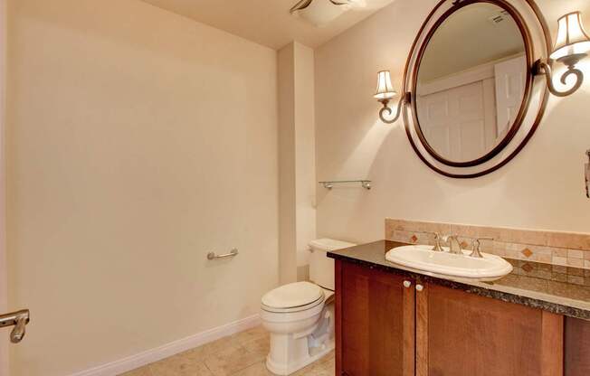 A bathroom with a toilet, sink, and mirror.