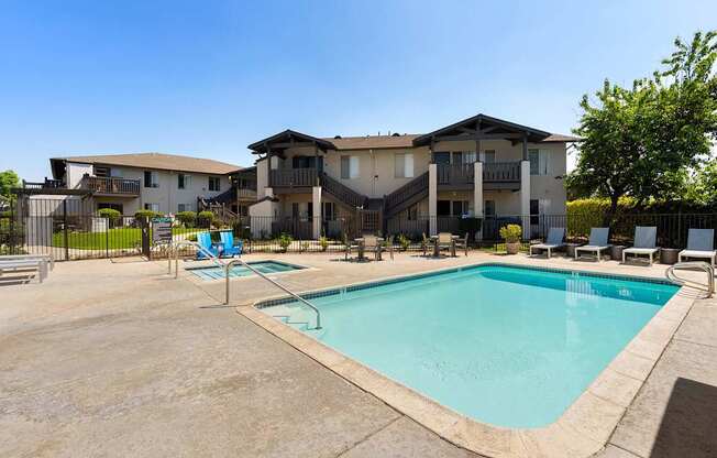 A large swimming pool in front of a multi-story apartment building.
