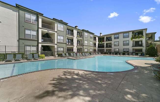A large swimming pool is surrounded by apartment buildings.
