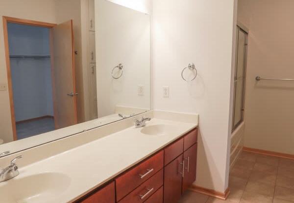 A bathroom with a sink, mirror, and cabinets.