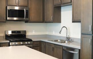 a kitchen with a stove a sink and a microwave at Loma Villas Apartments in San Bernardino, CA