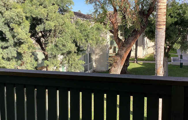 A view from a balcony looking out at a tree and a house.