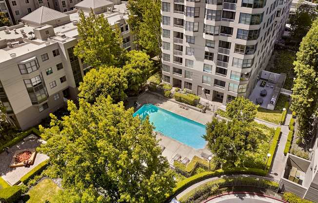 A swimming pool surrounded by trees and buildings.