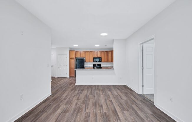 a living room and kitchen with wood floors and white walls