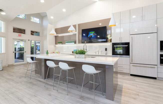 a kitchen with white cabinets and a large island with three stools