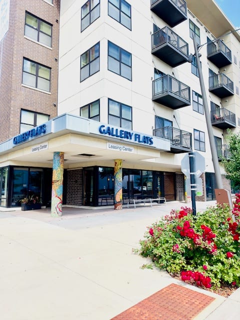 an apartment building with a sidewalk and flowers in front of it