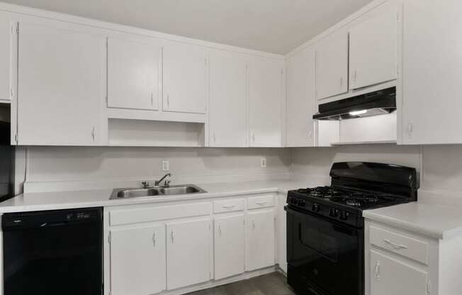 an all white kitchen with black appliances and white cabinets