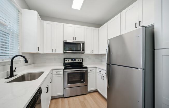 a kitchen with white cabinets and a stainless steel wall