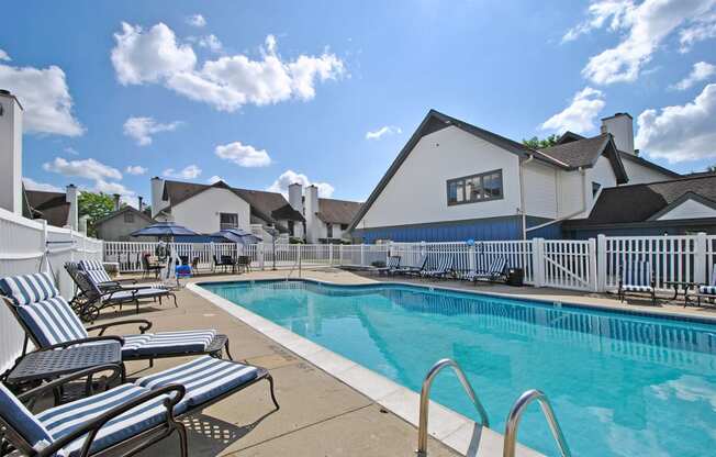 resort style swimming pool is next to building and lounge chairs