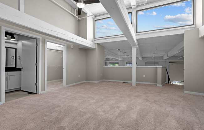 an empty living room with windows and a kitchen at Spinning Mill Lofts, Clayton, NC 27520