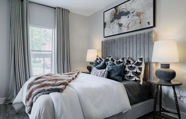 a bedroom with a large bed with pillows and a grey headboard