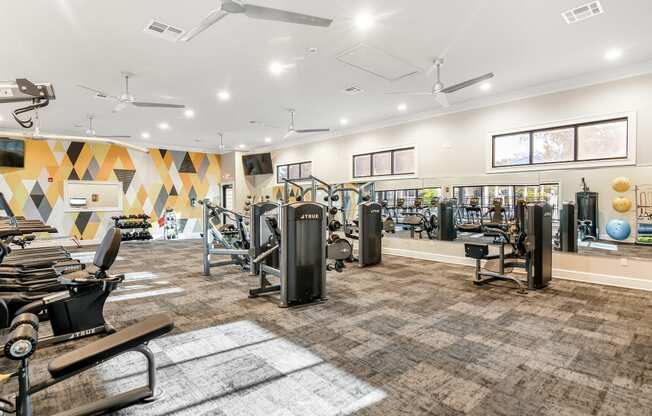 a gym with cardio machines and weights on a carpeted floor at Crossgates Apartment Homes, Starkville, Mississippi