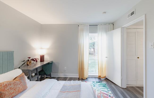 a bedroom with a bed and a desk and sliding glass doors