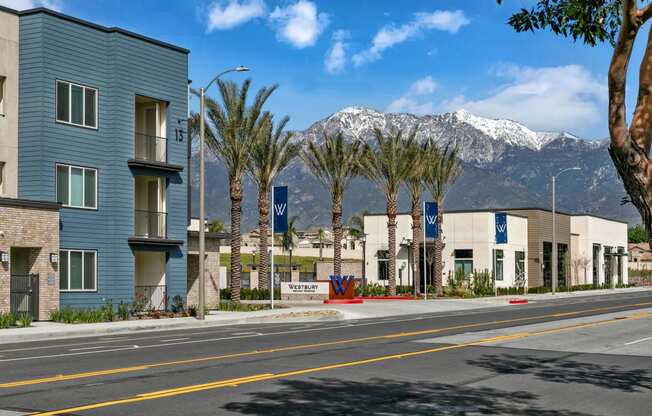 a city street with buildings and palm trees and mountains in the backgroundat Westbury Apartments, California, 91739