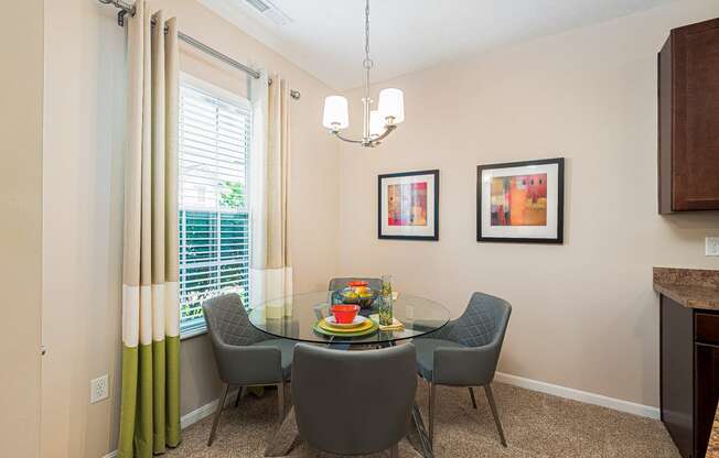 a dining room with a glass table and chairs and a window