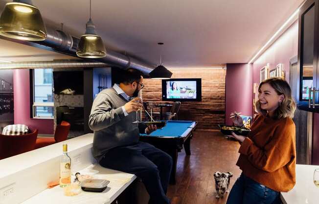 a man and a woman in a room with a pool table and tv