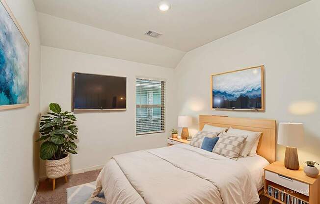 A bedroom with a bed, nightstand, and a painting on the wall.