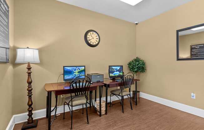 an office with a desk with two computers and a clock on the wall