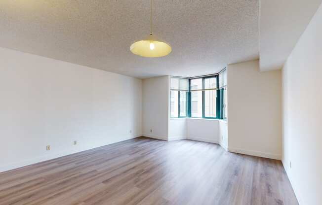 an empty living room with hardwood floors and a large window
