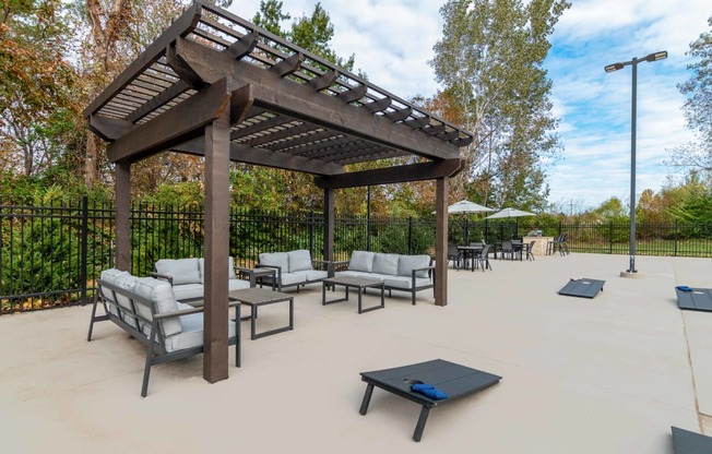 a patio with couches and tables and a wooden pavilion