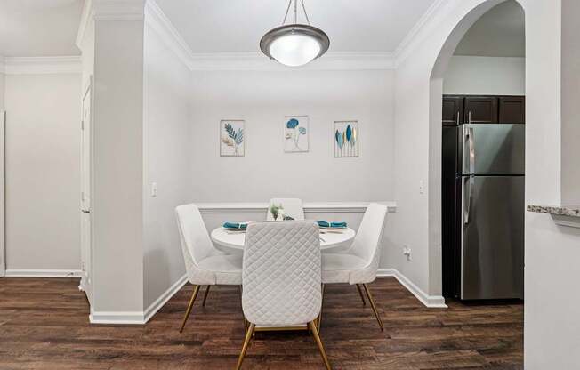 A dining room with a table set for two and a fridge in the corner.