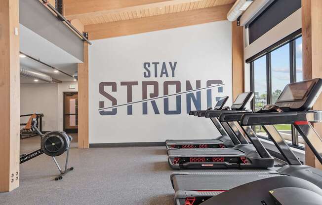 A gym with treadmills and a wall that says "Stay Strong".