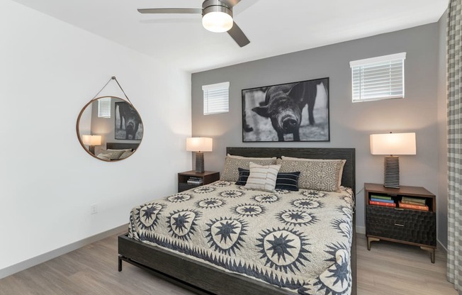 A bedroom with a bed, two lamps, and a ceiling fan.