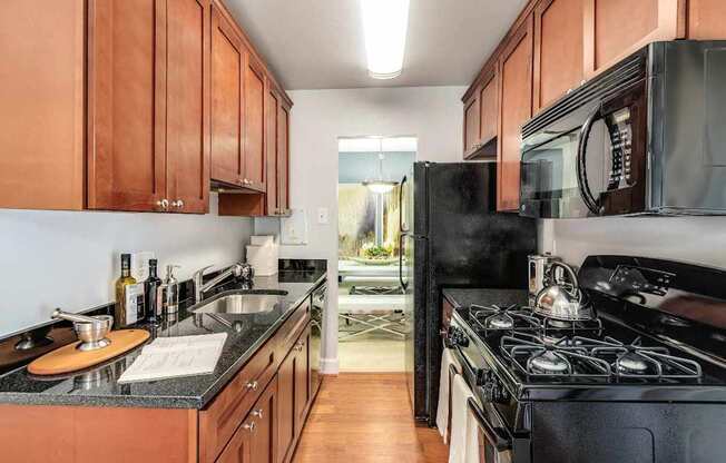 A kitchen with black appliances and wooden cabinets.