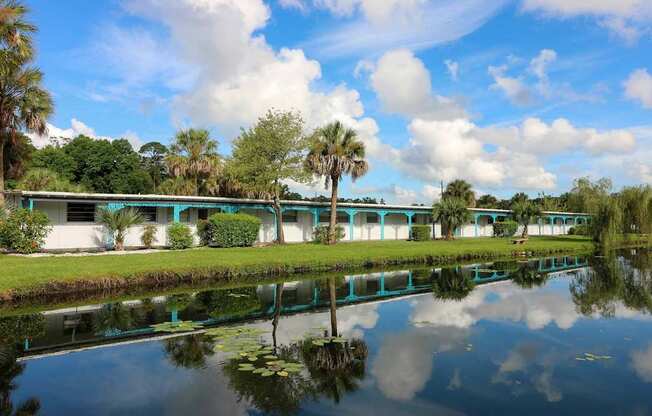 A serene landscape with a building, trees, and a reflective body of water.