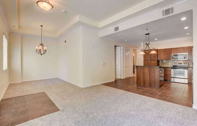 A spacious living room with a kitchen area in the background.