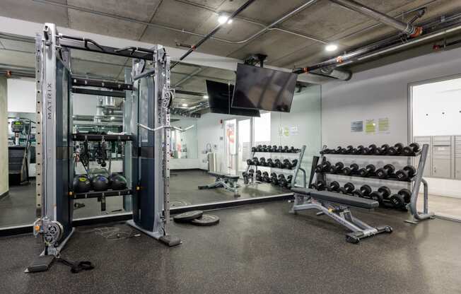 a gym with weights and a tv on the wall